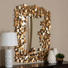 a mirror sitting on top of a wooden table next to a lamp and vases