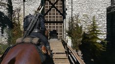 a man riding on the back of a brown horse down a wooden walkway next to a white brick building