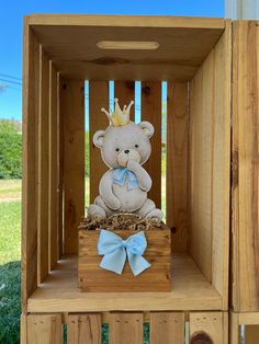 a teddy bear in a wooden crate with a blue bow on it's head