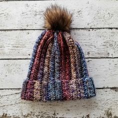 a multicolored knit hat with a fur pom - pom on top