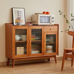 a microwave sitting on top of a wooden cabinet next to a chair and potted plant