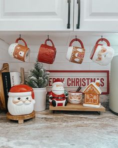 santa clause mugs are hanging on the kitchen counter with other christmas decorations and gifts