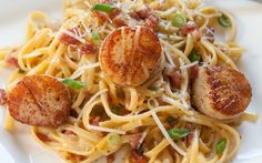 scallops and pasta on a white plate with green pepper sprinkles