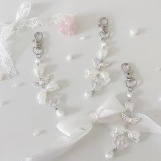 several different types of key chains on a white surface with flowers and pearls around them