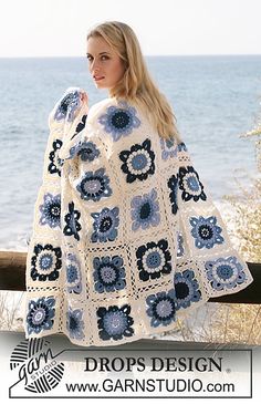 a woman wearing a blue and white crocheted granny's afghan with flowers on it