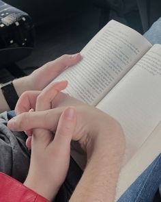 a person is reading a book while sitting in a car with their hands on the open book