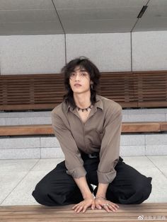 a man sitting on top of a wooden bench in front of a wall with benches behind him