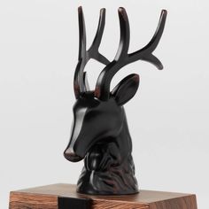 a black deer head on top of a wooden block