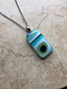 This is a fun, colorful, retro, mod fused glass pendant necklace, with  opalescent glass in  white, lime green, turquoise and blues.  The pendant is approximately .75" x 1.50" and comes on a 18" chain with lobster clasp. Caring for fused glass jewelry: To clean, use a soft cloth. Do not use harsh chemicals to clean. Should not be submerged in water, and should be removed when bathing. While fused glass is much stronger, use care when handling as can still break if dropped on hard surface.  Please contact me with any questions, changes or modifications.  Thank you so much for stopping at my shop! Fused Glass Jewelry Pendants, Modern Turquoise Glass Jewelry, Unique Green Necklace With Rectangular Pendant, Modern Blue Rectangular Necklace, Fused Glass Pendant Necklace, Fusing Glas, Fused Glass Necklace, Art Glass Jewelry, Glass Fusion