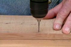 a person using a drill to cut wood with a piece of wood in front of them