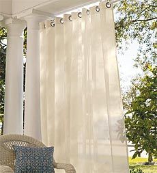 an outdoor patio with white curtains and wicker furniture