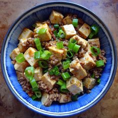 a blue bowl filled with tofu and green onions