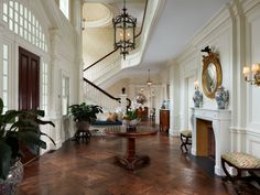 a living room with wooden floors and white walls, along with potted plants on either side of the fireplace