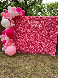 a pink and white backdrop with balloons in the shape of numbers on it, next to a sign that says 2012