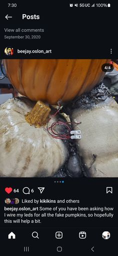 an orange pumpkin sitting on top of a pile of white and black rocks with wires attached to it