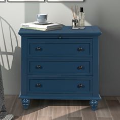 a blue chest of drawers in a room with two pictures on the wall above it