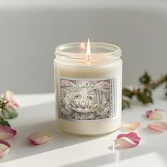 a white candle sitting on top of a table next to flowers