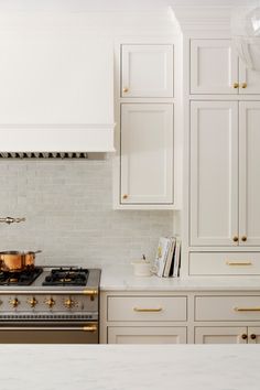 a stove top oven sitting inside of a kitchen next to white cabinets and counter tops