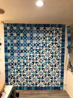 a blue and white quilt hanging on the wall