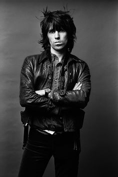 a black and white photo of a man with his arms crossed wearing a leather jacket