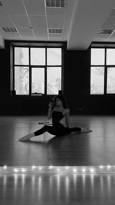 a woman sitting on the floor taking a selfie with her cell phone in an empty room