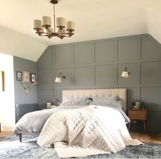 a bed sitting in a bedroom under a chandelier next to a dresser and lamp