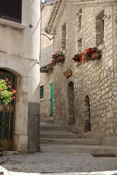 an alley way with stone buildings and flowers