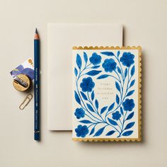 a blue and white greeting card next to a pencil