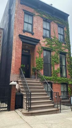 an old brick building with ivy growing on it's side and stairs leading up to the front door