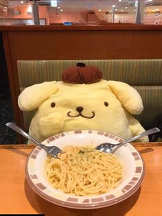 a teddy bear sitting at a table with a bowl of spaghetti