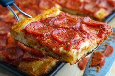 a slice of pepperoni pizza being lifted from a pan