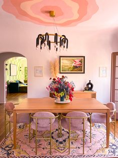 a dining room with pink chairs and a wooden table