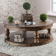 a round wooden table sitting on top of a white rug in front of a brick wall