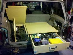 an open trunk in the back of a van with tools and other items inside it