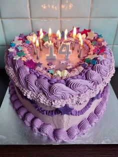 a birthday cake with purple icing and lit candles