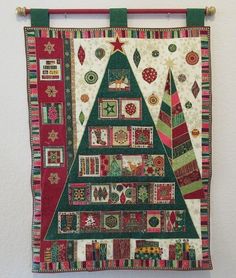 a quilted christmas tree hanging on a wall with red and green trimmings