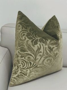 a white couch with a green and gold pillow on it's backrests