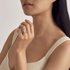 a woman wearing a diamond ring with her hand on her shoulder and looking off to the side