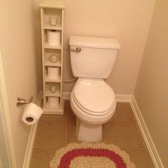 a white toilet sitting in a bathroom next to a shelf filled with toilet paper and rolls