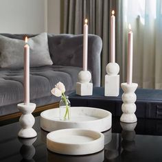 candles are lit on a table in front of a gray couch and black coffee table