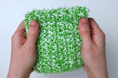 two hands holding a green and white crocheted object