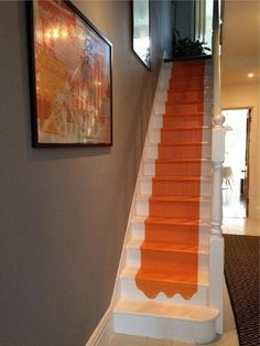 an orange carpeted staircase leading up to a framed painting on the wall above it