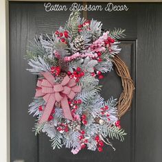 a christmas wreath on the front door with red berries, pine cones and evergreens