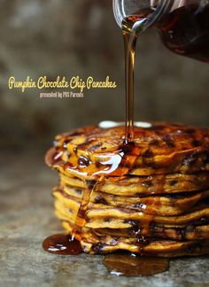 a stack of pancakes with syrup being poured on top and drizzled over them