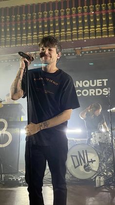 a man standing on top of a stage holding a microphone in his hand and singing