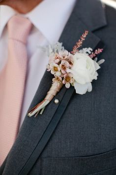 a man wearing a suit and tie with a boutonniere on his lapel