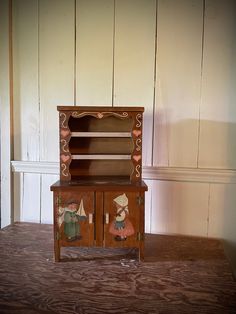 an old fashioned wooden cabinet with two dolls on it's front and back doors