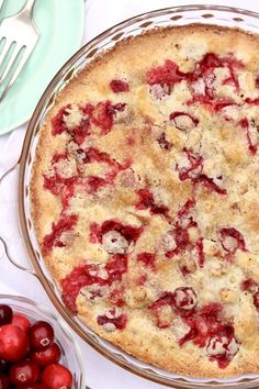 a pie sitting on top of a glass pan next to cherries and a fork