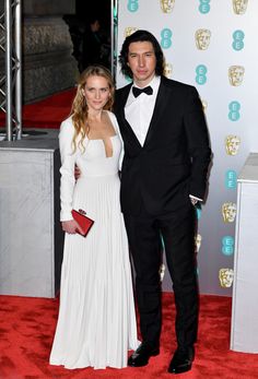 a man in a tuxedo standing next to a woman on a red carpet