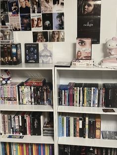 a book shelf filled with lots of books next to a wall covered in pictures and posters